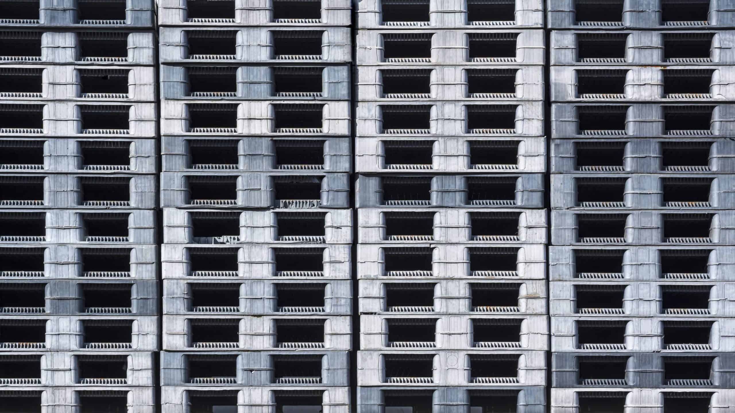 Stack of many plastic shipping pallets background in factory warehouse